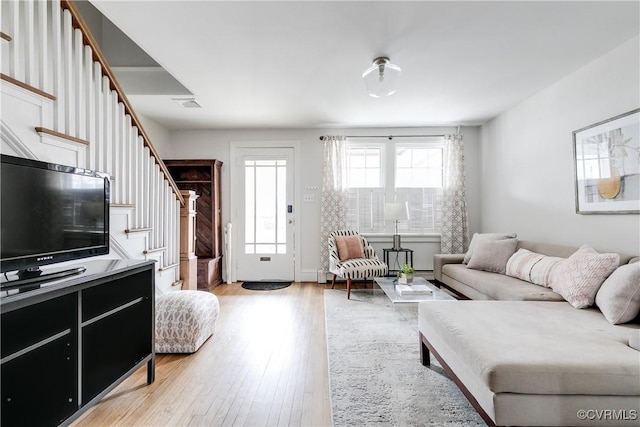 living area with light wood-style floors, visible vents, and stairway