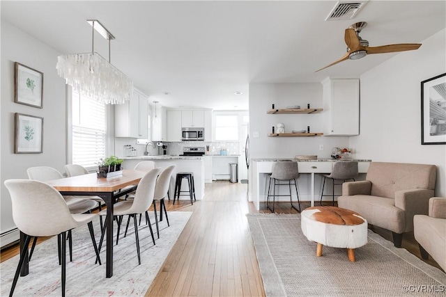 dining space with visible vents, ceiling fan, and light wood finished floors