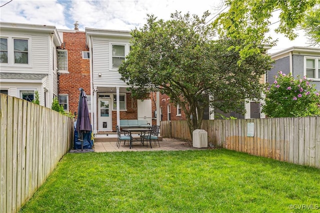 back of house featuring a patio area, a fenced backyard, brick siding, and a yard