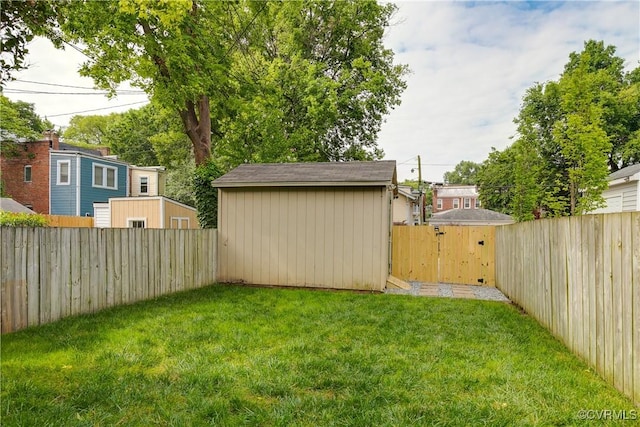 view of yard with an outdoor structure, a fenced backyard, and a gate