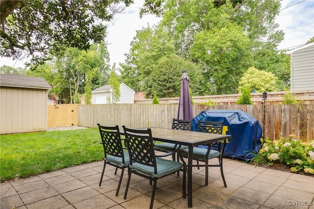 view of patio with a storage unit, outdoor dining space, a grill, a fenced backyard, and an outdoor structure