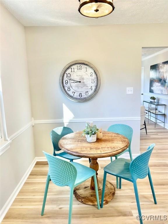 dining area featuring a textured ceiling, baseboards, and wood finished floors