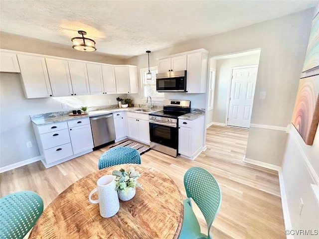 kitchen with appliances with stainless steel finishes, white cabinets, a sink, and light countertops