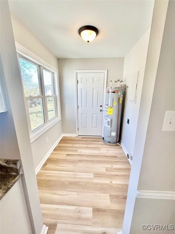 interior space featuring baseboards, water heater, and light wood finished floors