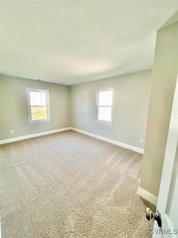 empty room featuring a healthy amount of sunlight, baseboards, and light colored carpet