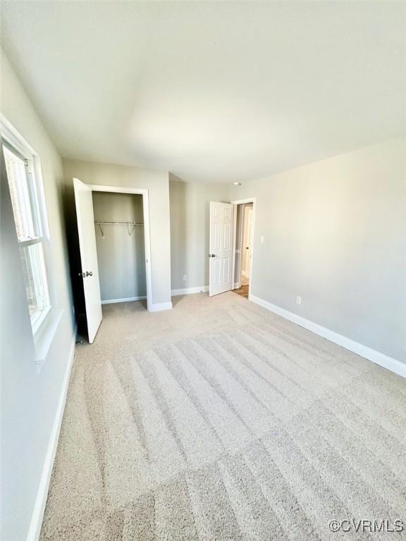 unfurnished bedroom with light carpet, baseboards, and a closet