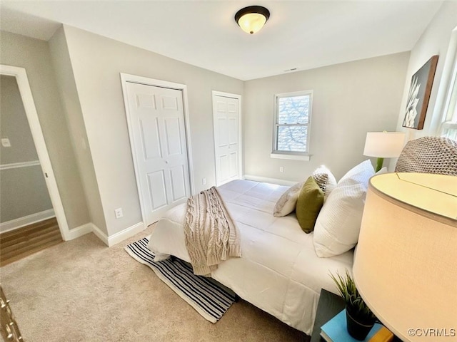 bedroom featuring carpet floors, baseboards, and two closets