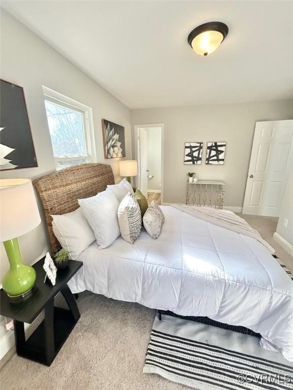 carpeted bedroom with ensuite bath and baseboards