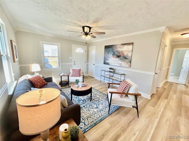 living area with ornamental molding, a textured ceiling, and wood finished floors