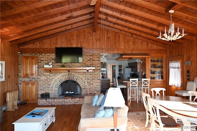 living area with vaulted ceiling with beams, wood walls, a fireplace, and wood finished floors