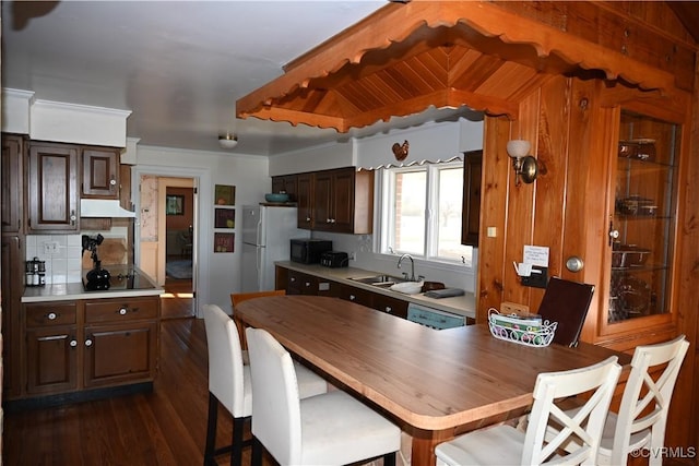 kitchen featuring dark brown cabinetry, black appliances, and light countertops