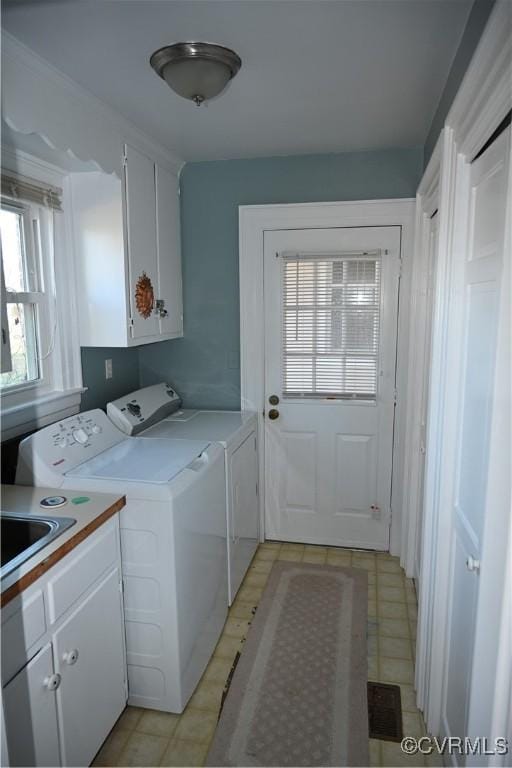 washroom with a sink, cabinet space, a wealth of natural light, and washer and dryer