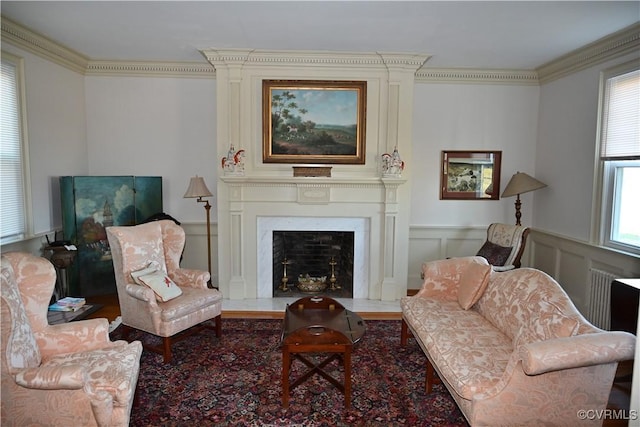 sitting room with wainscoting, a decorative wall, a fireplace, and crown molding