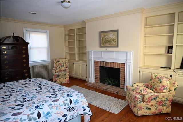 bedroom with dark wood-style floors, radiator, a fireplace, and ornamental molding