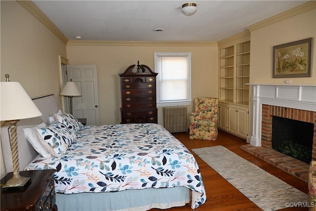 bedroom with radiator heating unit, a fireplace, ornamental molding, and dark wood-type flooring