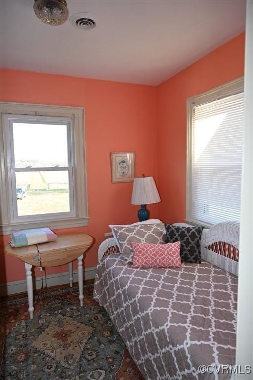 bedroom featuring multiple windows, visible vents, and baseboards