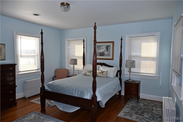 bedroom featuring visible vents, radiator heating unit, and wood finished floors