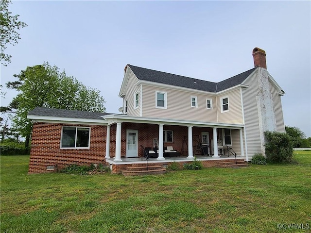 rear view of property with a yard, brick siding, a chimney, and a porch