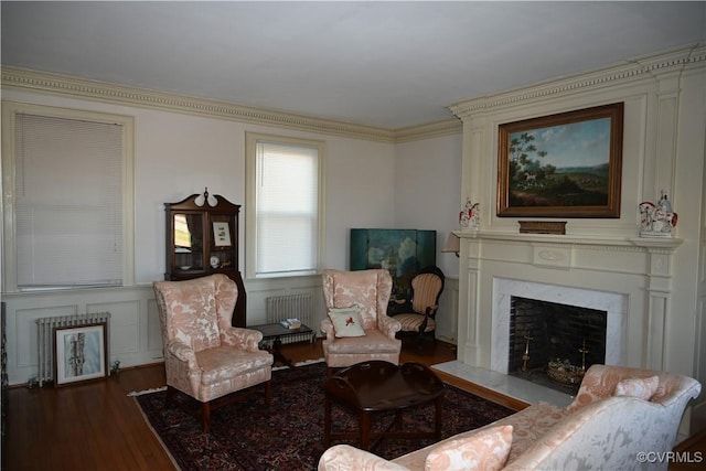 living area featuring a fireplace with flush hearth, crown molding, and wood finished floors