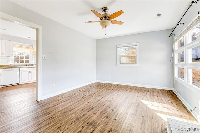 unfurnished room with baseboards, plenty of natural light, visible vents, and light wood-style floors