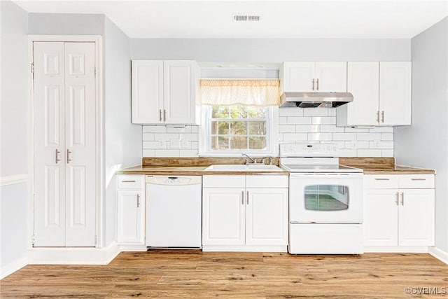 kitchen with white appliances, light wood-style flooring, under cabinet range hood, white cabinetry, and a sink