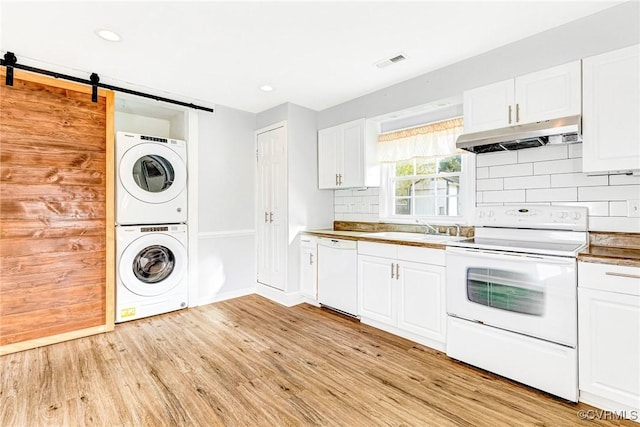 kitchen with visible vents, stacked washer / dryer, a sink, white appliances, and under cabinet range hood