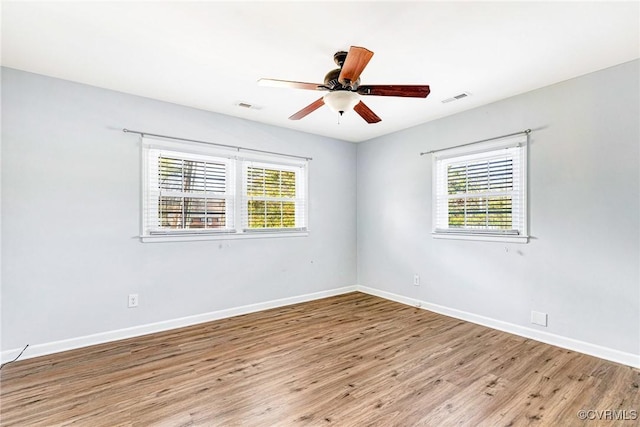 empty room with visible vents, baseboards, ceiling fan, and wood finished floors