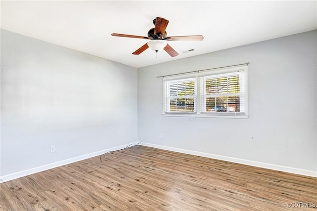 unfurnished room with baseboards, visible vents, ceiling fan, and wood finished floors