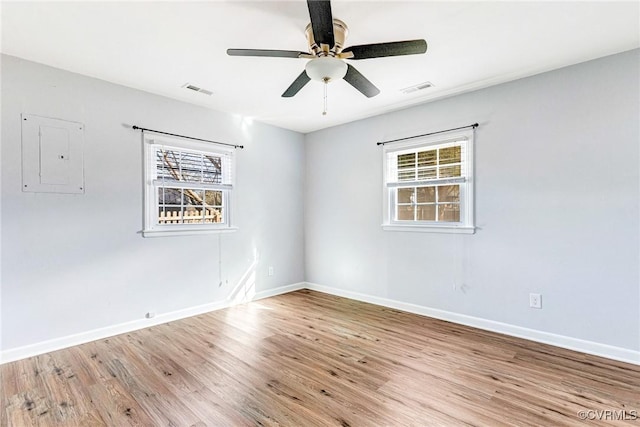 spare room featuring visible vents, light wood-type flooring, plenty of natural light, and electric panel