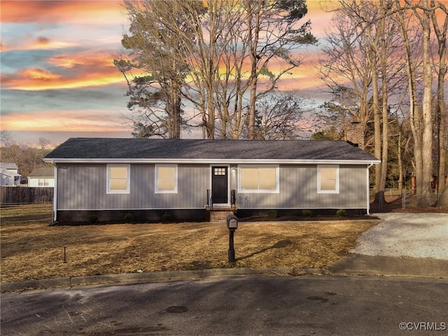 view of front of property featuring a lawn, a shingled roof, and fence