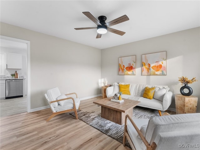 living area with light wood-style floors, baseboards, and ceiling fan