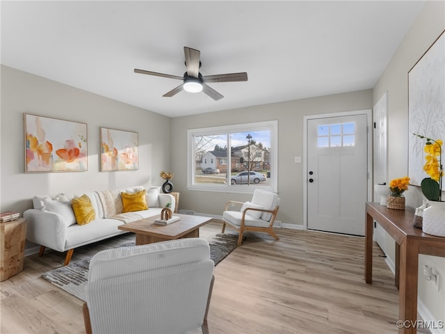 living area featuring a ceiling fan, light wood-style floors, and baseboards