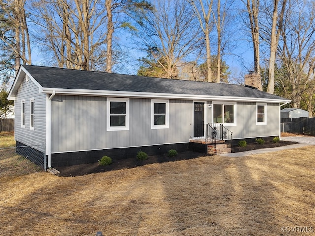 view of front of house with a shingled roof, a chimney, and fence