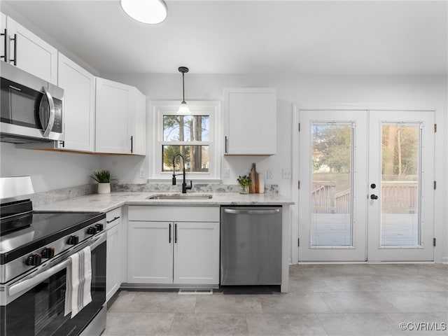 kitchen with a sink, light stone counters, white cabinetry, french doors, and appliances with stainless steel finishes