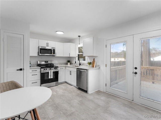 kitchen with light countertops, appliances with stainless steel finishes, french doors, white cabinets, and a sink