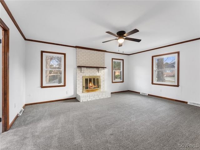 unfurnished living room with crown molding, a brick fireplace, visible vents, and carpet floors