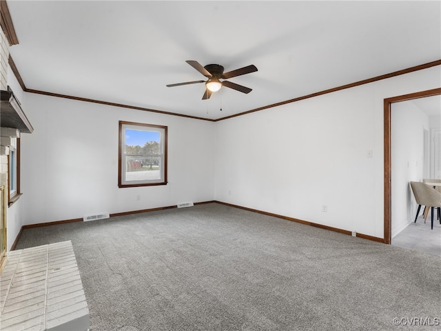 carpeted empty room featuring visible vents, baseboards, ornamental molding, and a ceiling fan