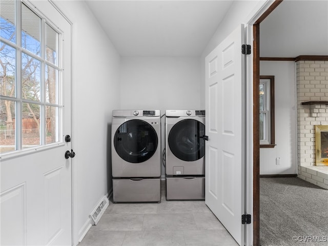 laundry room with washing machine and clothes dryer, visible vents, baseboards, laundry area, and a fireplace