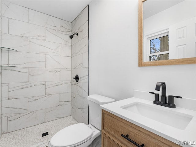 full bath featuring vanity, toilet, and tiled shower