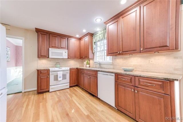 kitchen featuring light stone counters, tasteful backsplash, light wood-style floors, brown cabinetry, and white appliances