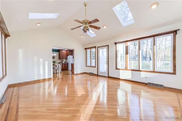 unfurnished living room with a skylight, visible vents, baseboards, light wood-style flooring, and ceiling fan