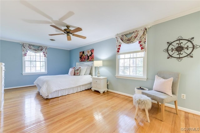 bedroom featuring baseboards, wood finished floors, and crown molding