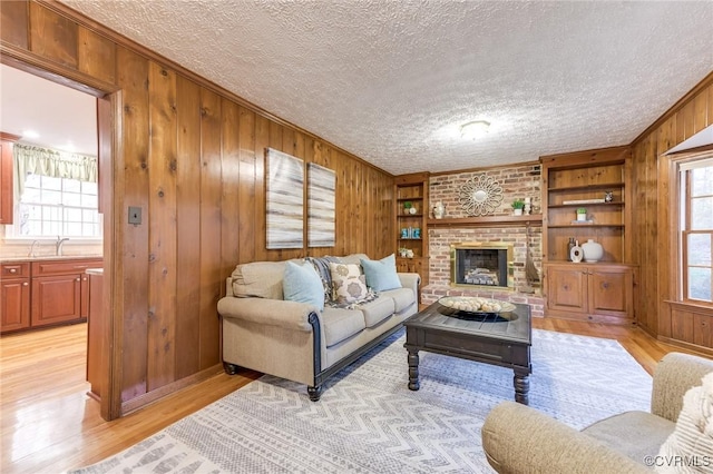 living area featuring light wood-style flooring, wooden walls, and a textured ceiling