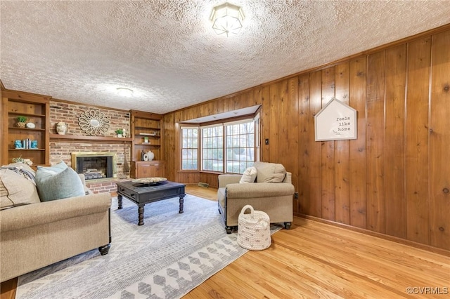 living room with built in features, wood finished floors, a textured ceiling, wood walls, and a fireplace