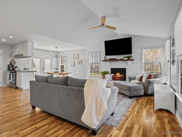 living room with plenty of natural light, vaulted ceiling, a fireplace, and light wood-style flooring