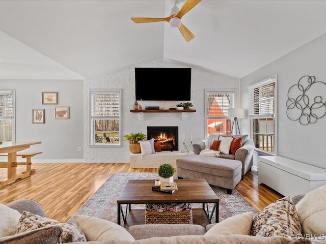 living area with lofted ceiling, a brick fireplace, plenty of natural light, and wood finished floors