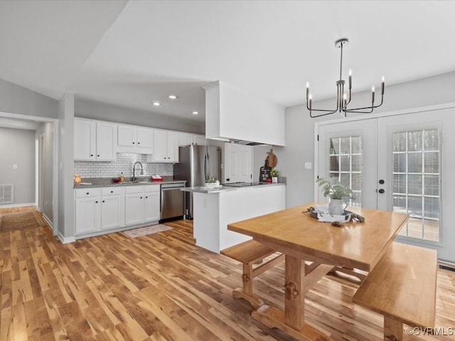 kitchen with stainless steel appliances, a sink, visible vents, light wood-style floors, and tasteful backsplash