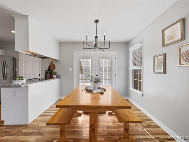 dining room featuring light wood-type flooring, french doors, baseboards, and an inviting chandelier