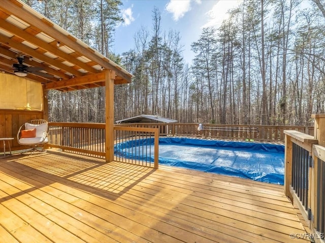 view of swimming pool featuring a deck, ceiling fan, and a fenced in pool