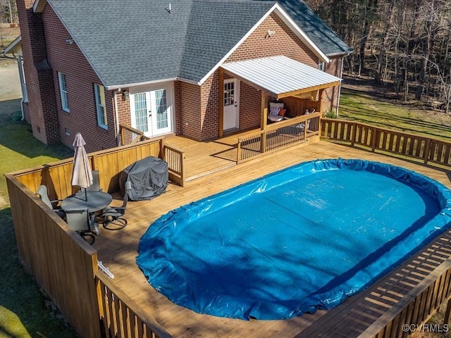 view of pool with french doors and a deck